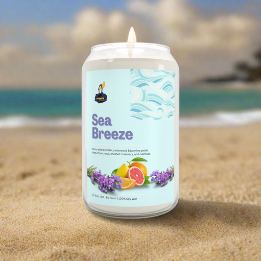 Candle labeled 'Sea Breeze' on a sandy beach with ocean view